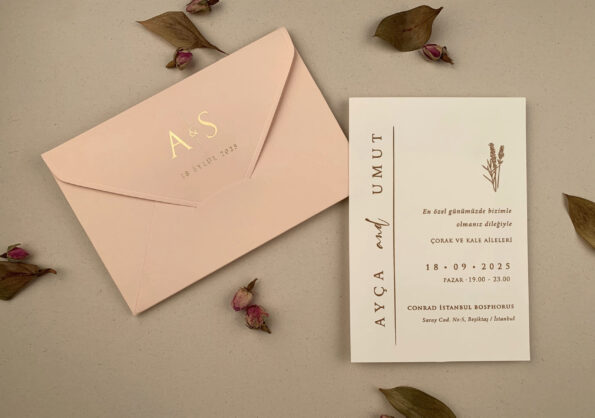 un plic roz și o invitatie albă cu flori si text auriu